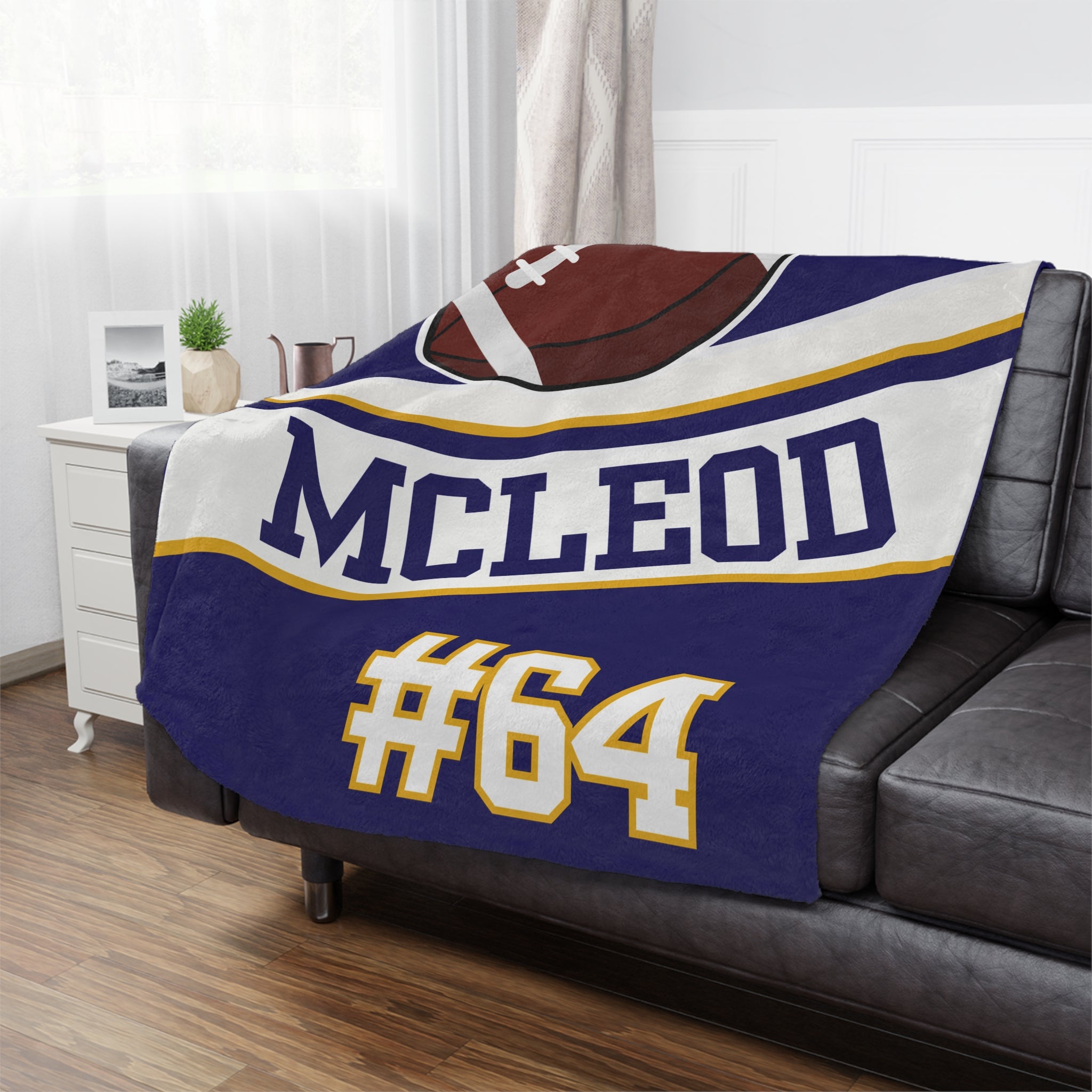 Blanket with 'MCLEOD #64' printed on it draped over a couch in a living room.