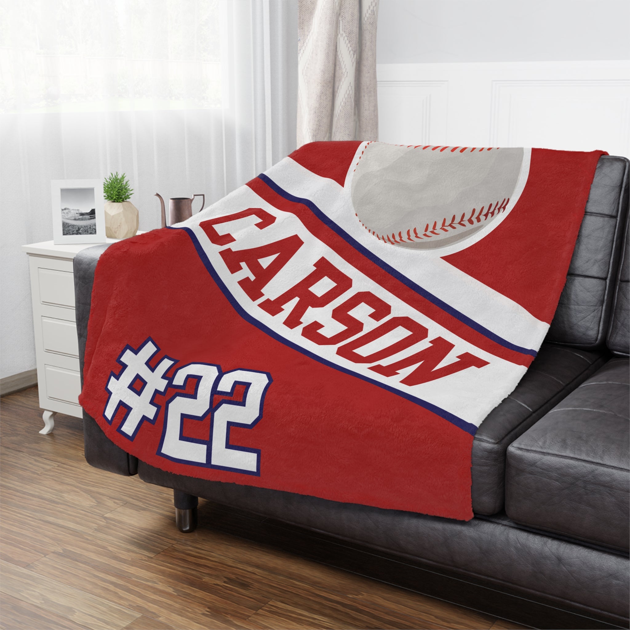 Red blanket with 'CARSON #22' printed on a gray couch in a living room.