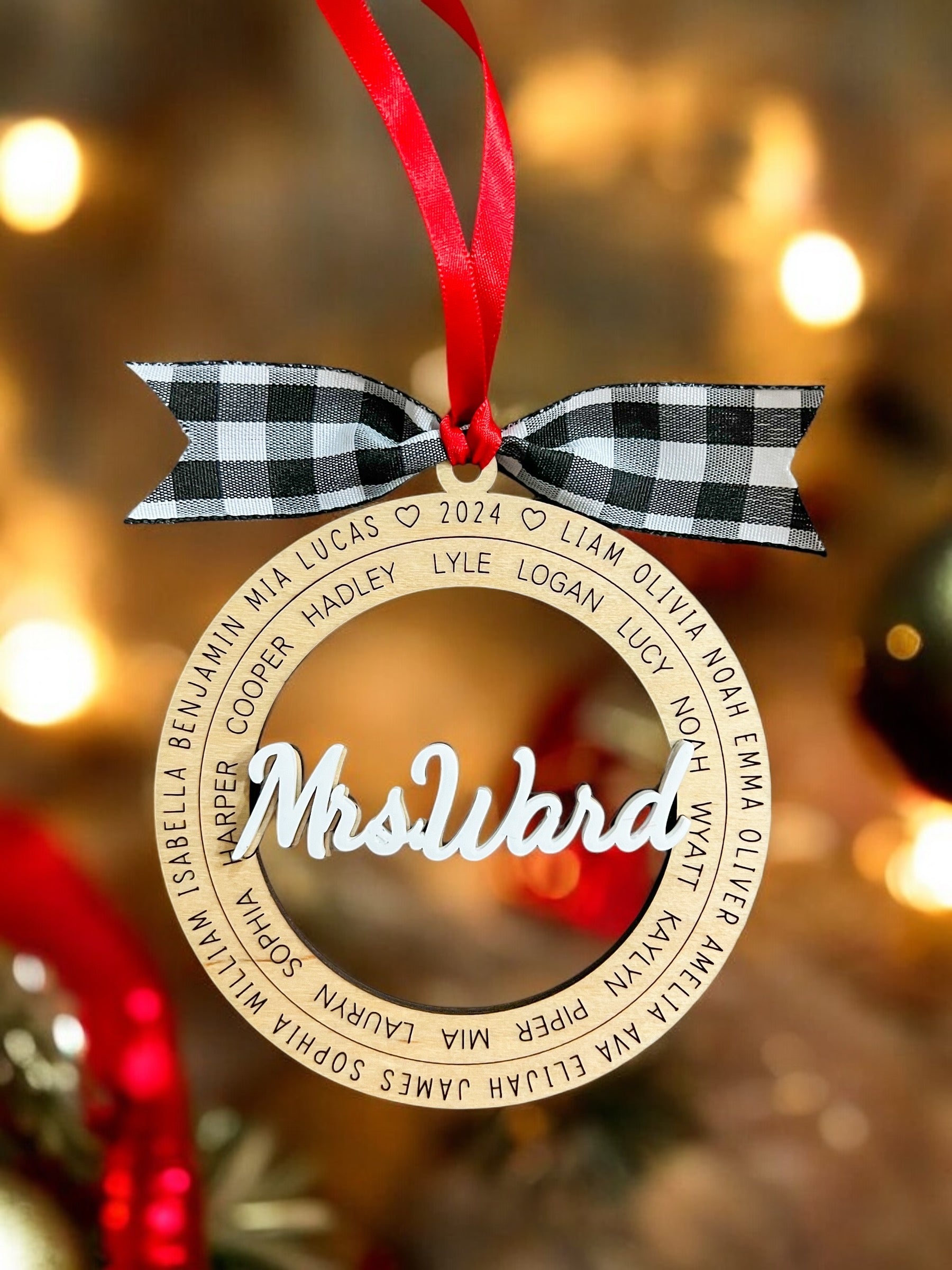 Decorative ornament with 'Mrs Ward' and names on a blurred Christmas background