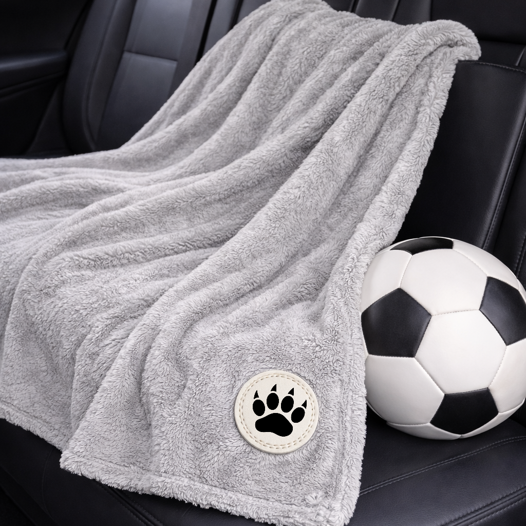 Gray fleece blanket with a paw print on a car seat next to a soccer ball