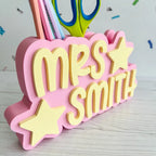 Pink holder with 'Mrs Smith' text and scissors on a light background