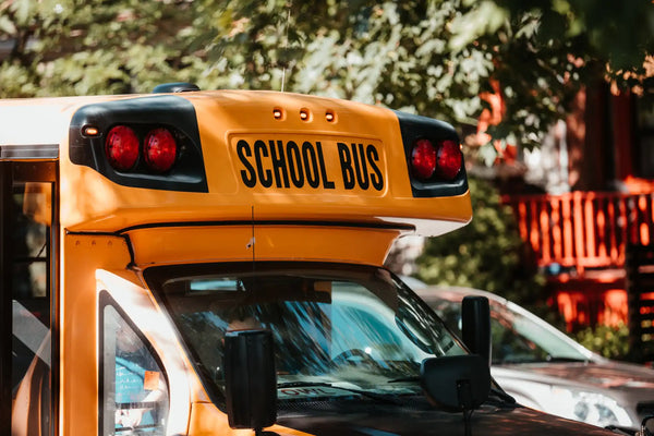 Yellow school bus with black roof and red taillights.